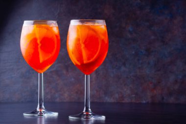 Koyu arkaplanda camlı Aperol sprey kokteyli. İki bardak dilimlenmiş portakallı aperol spreyi. Bardakta yaz kokteyli. Boşluğu kopyala