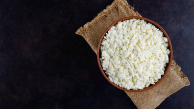 Çuval bezinde süzme peynir. Koyu bir arka planda taze süzme peynir. Siyah arka planda yumuşak peynir. Minimalizm. Üst Manzara. Boşluğu kopyala