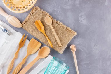 Sıfır atık. Eko çanta, cam ve gri arka planda ahşap çatal bıçak. Çevre dostu ahşap çatal bıçak takımı, çuval bezi ve mason kavanozu. Plastiksiz konsept. Üst Manzara. Boşluğu kopyala