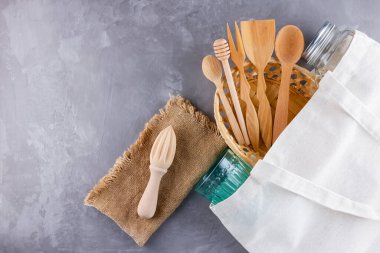Sıfır atık. Eko çanta, cam ve gri arka planda ahşap çatal bıçak. Çevre dostu ahşap çatal bıçak takımı, çuval bezi ve mason kavanozu. Plastiksiz konsept. Üst Manzara. Boşluğu kopyala