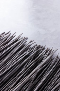 Gri arka planda siyah makarna. Çimento arka planında siyah spagetti. Mürekkepbalıklı çiğ spagetti. Yemek geçmişi konsepti. Üst Manzara. Boşluğu kopyala