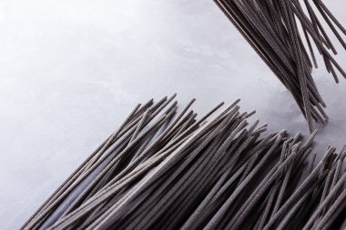 Gri arka planda siyah makarna. Çimento arka planında siyah spagetti. Mürekkepbalıklı çiğ spagetti. Yemek geçmişi konsepti. Üst Manzara. Boşluğu kopyala