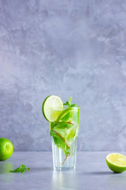 Limonlu mojito kokteyli ve uzun bardakta nane şekeri. Gri arka planda camlı taze mojito. Naneli kokteyli limonla tazeliyorum. Kaynamış su. Boşluğu kopyala