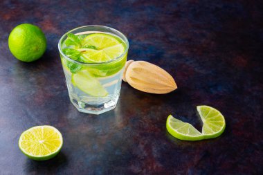 Limonlu kokteyl ve bardakta nane şekeri. Karanlık bir arka planda bir bardak mojito. Naneli kokteyli limonla tazeliyorum. Kaynamış su. Üst Manzara. Boşluğu kopyala