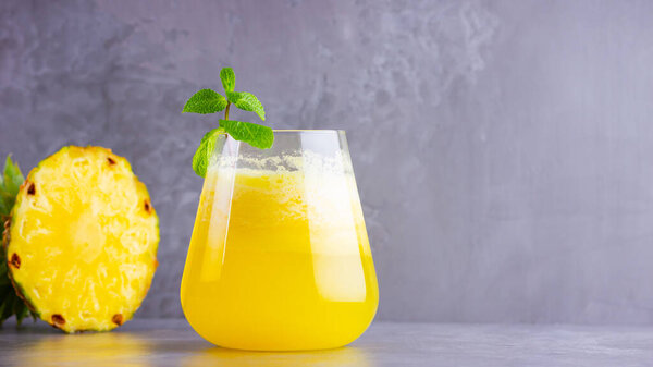 Ананасовый коктейль на сером фоне. Холодный ананасовый коктейль с мятой. Летний тропический коктейль. Здоровый напиток
