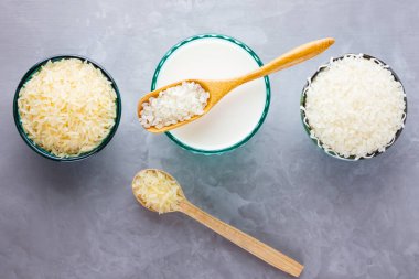 Gri arka planda pirinç sütü. Bardakta pirinç sütü ve pirinç tohumları. Çimento arka planında süt içermeyen vegan. Yükselişten gelen alternatif süt. Minimalizm. Boşluğu kopyala