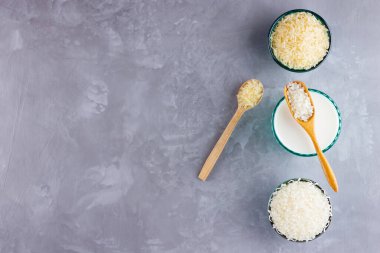 Gri arka planda pirinç sütü. Bardakta pirinç sütü ve pirinç tohumları. Çimento arka planında süt içermeyen vegan. Yükselişten gelen alternatif süt. Minimalizm. Boşluğu kopyala