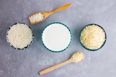 Gri arka planda pirinç sütü. Bardakta pirinç sütü ve pirinç tohumları. Çimento arka planında süt içermeyen vegan. Yükselişten gelen alternatif süt. Minimalizm. Boşluğu kopyala