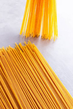 Gri arka planda sarı makarna. Çimento arka planında spagetti. Çiğ spagetti bolonez. Yemek geçmişi konsepti. Üst görünüm
