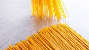 Gri arka planda sarı makarna. Çimento arka planında spagetti. Çiğ spagetti bolonez. Yemek geçmişi konsepti. Üst görünüm