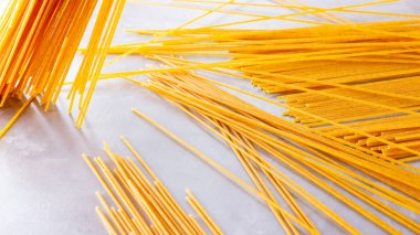 Gri arka planda sarı makarna. Çimento arka planında spagetti. Çiğ spagetti bolonez. Yemek geçmişi konsepti. Üst görünüm