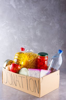 Bağış kutusu ve yiyecek. İçinde yağ, su, konserve yiyecek, mısır gevreği ve makarna olan karton bir kutu açın. Bağış konsepti. Market seti