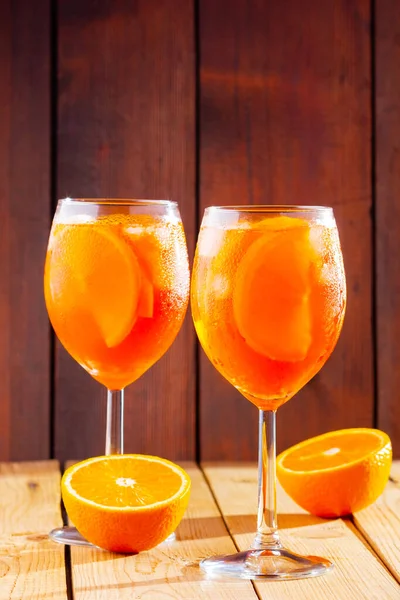 木製の背景にアペロールスプリッツカクテル オレンジ色の絞りスプリッツの2つのメガネがスライドしました 夏のカクテルをグラスで トレンディ ドリンク 素朴な様式 — ストック写真