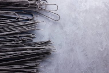 Gri arka planda siyah makarna. Çimento arka planında siyah spagetti. Mürekkepbalıklı çiğ spagetti. Yemek geçmişi konsepti. Üst Manzara. Boşluğu kopyala