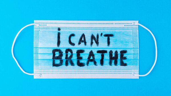 I CAN'T BREATHE on a surgical mask. Protective face mask with "I can't breathe" on a blue background. Concept Black Lives Matter. Copy space. Top view