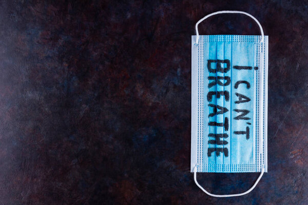 I CAN'T BREATHE on a surgical mask. Protective face mask with "I can't breathe" on a dark background. Concept Black Lives Matter. Copy space. Top view