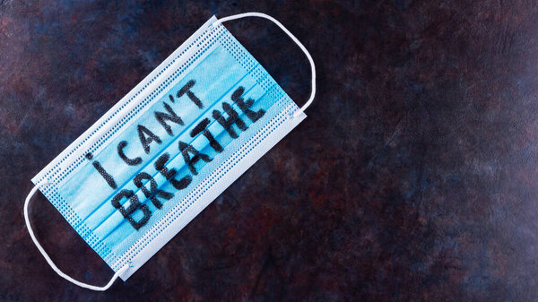 I CAN'T BREATHE on a surgical mask. Protective face mask with "I can't breathe" on a dark background. Concept Black Lives Matter. Copy space. Top view