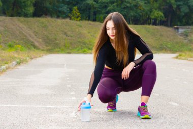Suyla antrenman yapan güzel bir genç kız. Kadın sporcu su içmek için mola verir. Yaz antrenmanı. Fitness, insanlar ve sağlıklı yaşam tarzı. Boşluğu kopyala