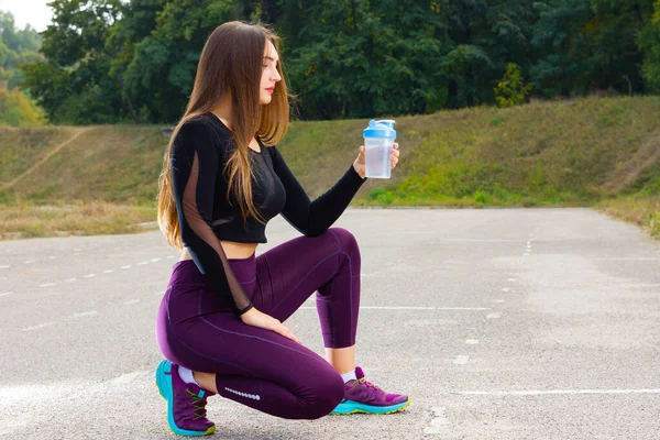 Beautiful young girl in running training with water. Woman athlete takes a break to drink water. Summer training. Fitness, people and healthy lifestyle. Copy space