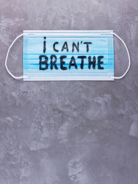 I CAN'T BREATHE on a surgical mask. Protective face mask with "I can't breathe" on a gray background. Concept Black Lives Matter. Copy space. Top view