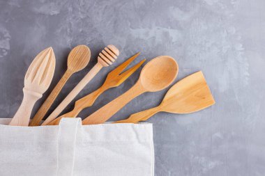 Sıfır atık. Pamuk eko çanta ve gri arka planda ahşap çatal bıçak takımı. Çevre dostu ahşap çatal bıçak takımı. Plastiksiz konsept. Minimalizm. Üst Manzara. Boşluğu kopyala