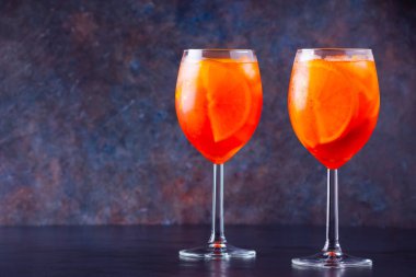 Koyu arkaplanda camlı Aperol sprey kokteyli. İki bardak dilimlenmiş portakallı aperol spreyi. Bardakta yaz kokteyli. Boşluğu kopyala