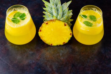 Karanlık bir arka planda ananas suyu. Bardakta detoks sıvısı var. Taze ananaslı ananas püresi. Siyah arka planda yaz içkisi. Üst Manzara. Boşluğu kopyala