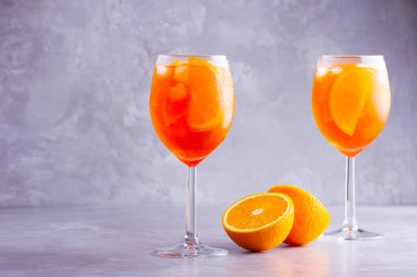 Gri arka planda Aperol sprey kokteyli. İki bardak portakallı aperol spreyi. Bardakta İtalyan kokteyli. Boşluğu kopyala