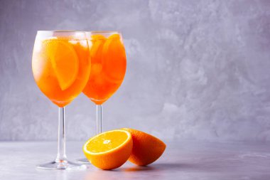 Gri arka planda Aperol sprey kokteyli. İki bardak portakallı aperol spreyi. Bardakta İtalyan kokteyli. Boşluğu kopyala