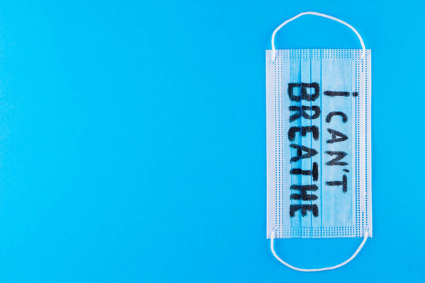 I CAN'T BREATHE on a surgical mask. Protective face mask with "I can't breathe" on a blue background. Concept Black Lives Matter. Copy space. Top view