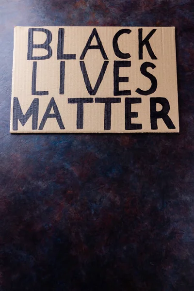 BLACK LIVES MATTER. No racism concept on a dark background. Cardboard banner with a text \