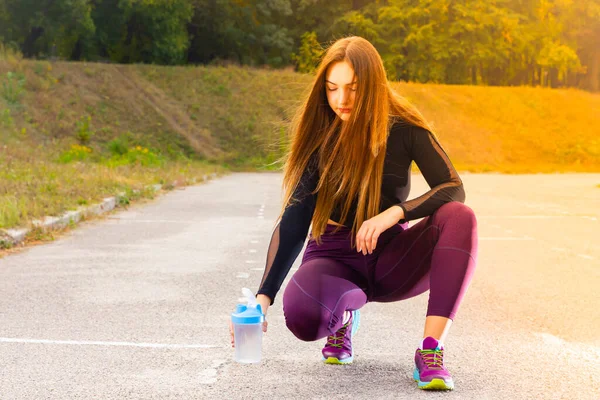 Beautiful young girl in running training with water. Woman athlete takes a break to drink water. Summer training. Fitness, people and healthy lifestyle. Copy space