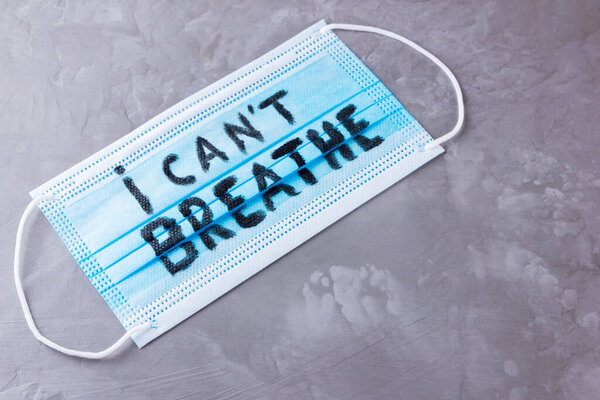 I CAN'T BREATHE on a surgical mask. Protective face mask with "I can't breathe" on a gray background. Concept Black Lives Matter. Copy space. Top view