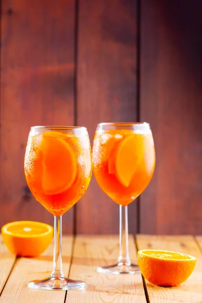 木製の背景にアペロールスプリッツカクテル オレンジ色の絞りスプリッツの2つのメガネがスライドしました 夏のカクテルをグラスで トレンディ ドリンク 素朴な様式 — ストック写真