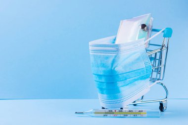 Koruyucu tıbbi maskeli alışveriş arabası. Alışveriş arabasının termometresi ve not defteri. Süpermarkette güvenli alışveriş. Karantina konsepti. Boşluğu kopyala