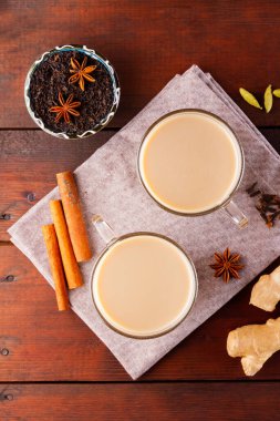 Keten peçetede Masala çayı. Geleneksel Hint içeceği. Ahşap arka planda baharatlar olan Masala çayı. Üst görünüm