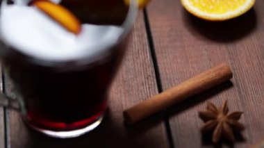 Ahşap arka planda sıcak şarap, yukarıdan manzara. Sonbahar sıcak şarap ve baharatlar. Kırsal tarzda sıcak bir Noel içeceği. Yavaş çekim