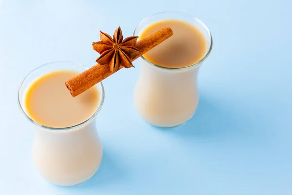 Tea with milk and spices on a blue background. Masala chai in turkish tea cups. Indian national drink on a pastel background. Top view