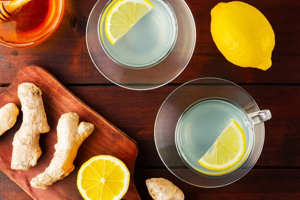 Limonlu zencefil çayı. Ahşap zemin üzerinde limon ve bal olan iki fincan zencefil çayı. Üst görünüm