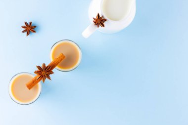 Mavi arka planda süt ve baharatlı çay. Türk çay fincanlarında Masala chai. Pastel arka planda Hindistan ulusal içeceği ve süt sürahisi. Uzayı kopyala Üst görünüm