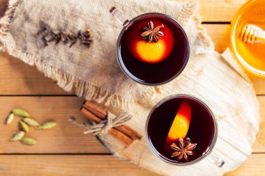 Ahşap arka planda sıcak şarap. Sonbahar, çuval bezinde şarap ve baharat. Kırsal tarzda sıcak bir Noel içeceği