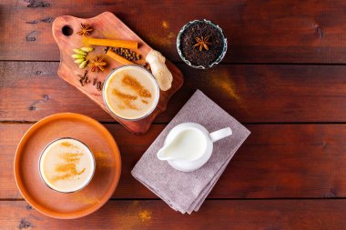 İki bardak Masala çayı ve çeşitli malzemeler. Tahta tahtada Masala çayı. Sütlü çay ve baharat. Uzayı kopyala Üst görünüm