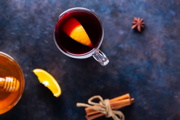 Christmas mulled wine on a dark background. Mulled wine in glass with cinnamon, oranges and honey. Christmas hot drink