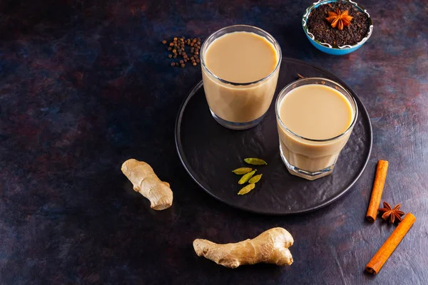 マサラチャイ茶 伝統的なインドの飲み物 ブラックプレート上の様々なスパイスとマサラ茶 黒を基調とした2つの透明ガラスとマサラティー — ストック写真