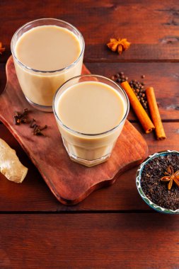 Sütlü çay ve baharat. Tahta tahtada Masala çayı. Bunu yapmak için iki bardak Masala çayı ve malzemesi. Uzayı kopyala Üst görünüm
