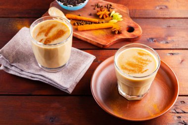 İki bardak Masala çayı ve çeşitli malzemeler. Tahta tahtada Masala çayı. Sütlü çay ve baharat. Uzayı kopyala Üst görünüm