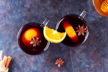 Karanlık bir arka planda sıcak şarap. İki bardak sonbahar şarabı ve malzemesi. Şarap ve ballı Noel içkisi