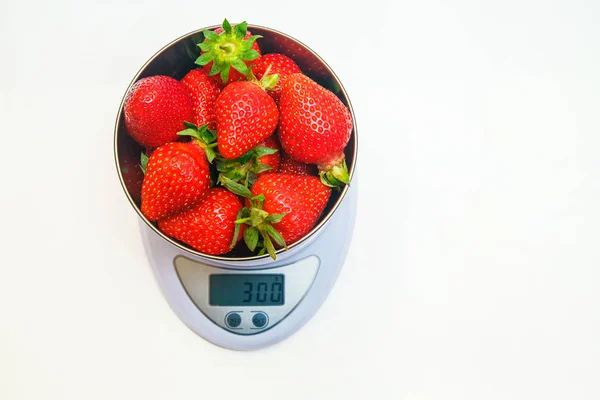 fresh ripe strawberries in a bowl on the scales. Weight - 300 g