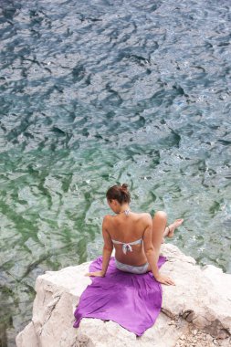 Güneş banyosu. Çekici bir kız güzel bir kayalık plajda dinleniyor. Yaz, seyahat, tatil, tatil