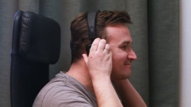 Bir sandalyede oturan bir genç adam kulaklıklar müzik inanılmaz müzik ritmi hissi dinlerken. İş yerinde müzikal ilham